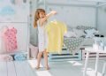Beautiful little girl choosing a dress in the kids room