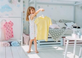 Beautiful little girl choosing a dress in the kids room