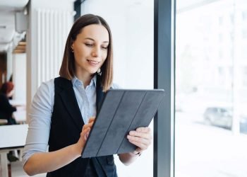 Female employer holding digital tablet while looking forward to meeting with partners