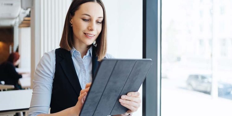 Female employer holding digital tablet while looking forward to meeting with partners