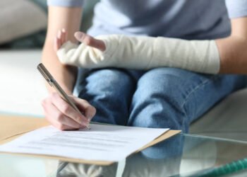 Disabled woman with bandaged arm signing document