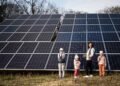 Mother with three kids on the background of solar panels. Eco energy.