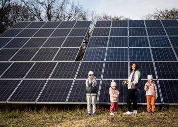 Mother with three kids on the background of solar panels. Eco energy.