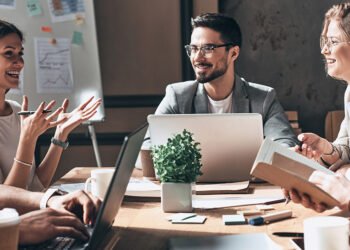 Happy business team working together while sitting at the desk in office