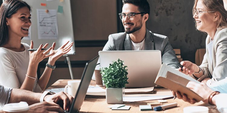 Happy business team working together while sitting at the desk in office